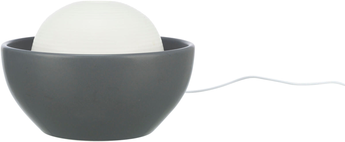 Graue Schale mit einer weißen, strukturierten Kugel darin, verbunden mit einem weißen Kabel.
