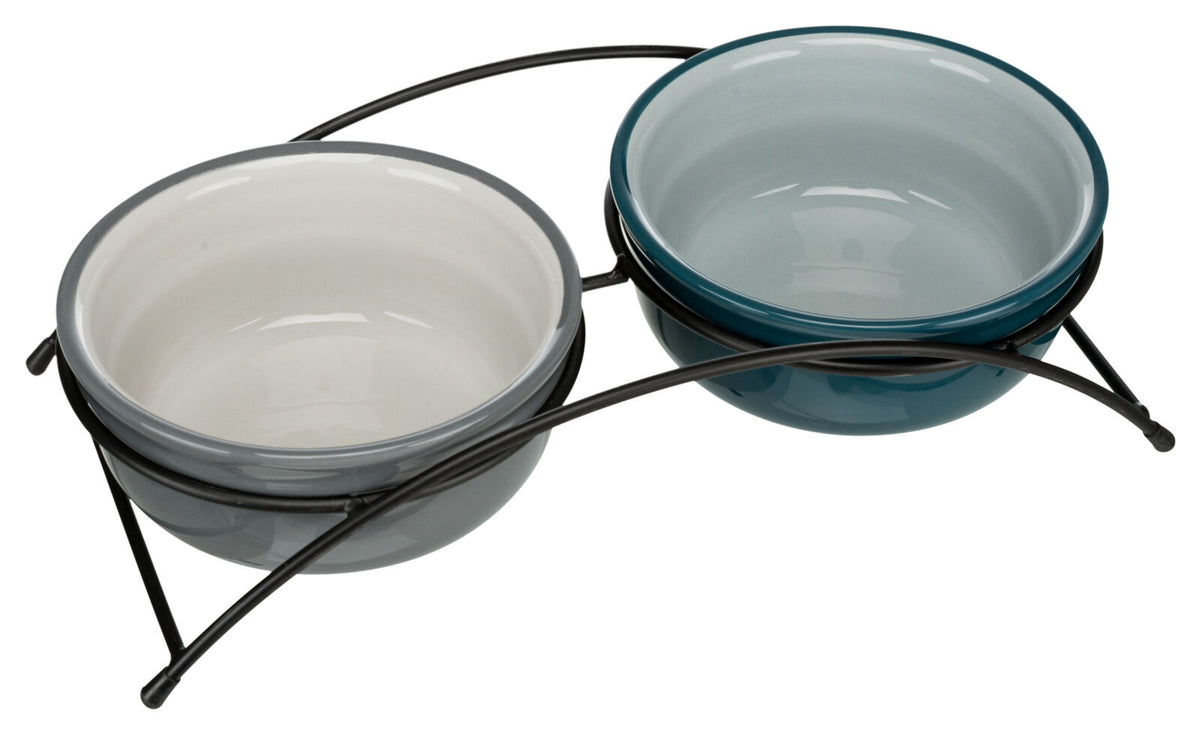 Zwei Keramikschalen in Weiß und Blau sitzen auf einem schwarzen Metallgestell mit gebogenem Design.