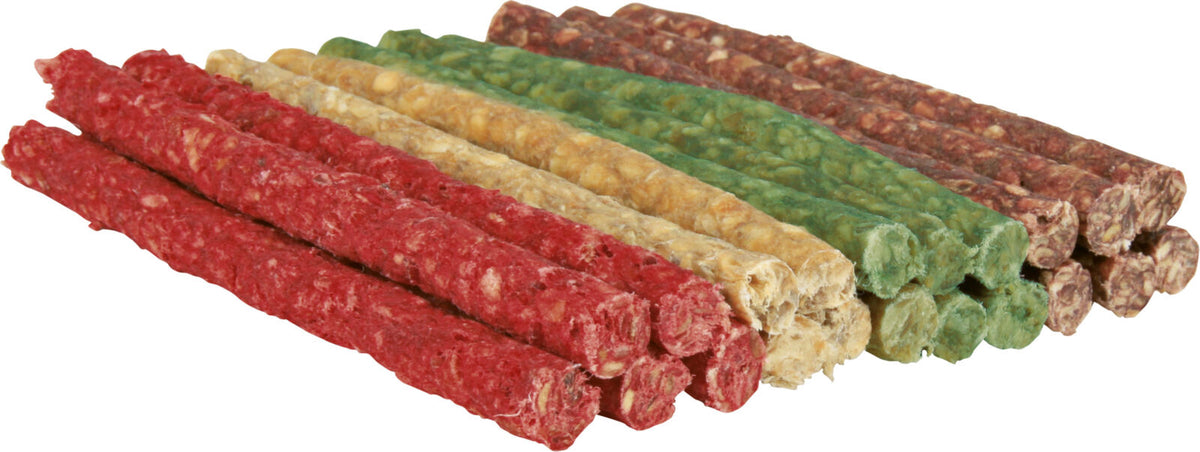 Bunte Hundesnacks in Grün, Rot, Gelb und Braun liegen gestapelt auf einer hellen Oberfläche.