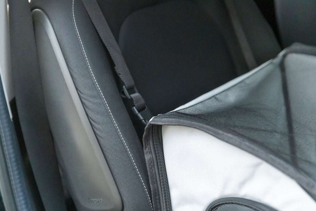 Schwarzer Autogurt mit schwarzem Netz an grauem Sitz befestigt.