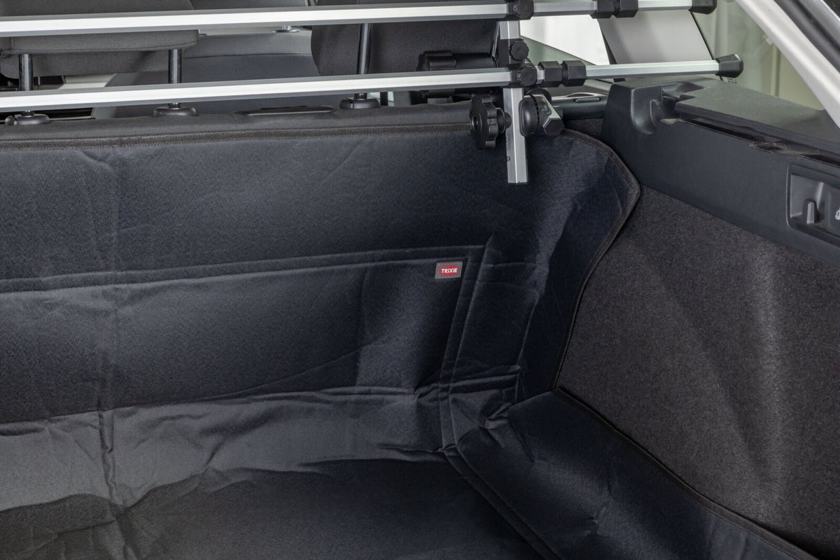 Schwarze Kofferraumauskleidung in einem Auto mit sichtbarem Schutzgitter und einem kleinen roten Etikett.