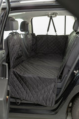 Schwarze, gesteppte Autoschondecke bedeckt die Rückbank und Innenraum eines Autos, Kopfstützen und Sicherheitsgurte sichtbar.