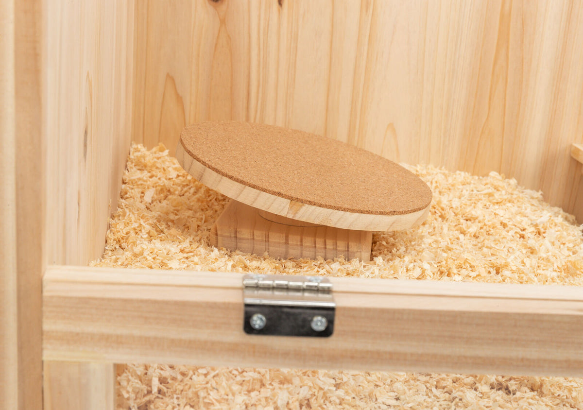 Holzbox mit Hobelspänen, darin ein rundes Brett auf einer erhöhten Basis.