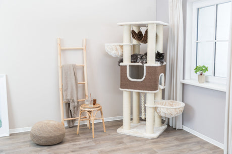 Kratzbaum aus beigem und braunem Stoff mit mehreren Plattformen und zwei Katzen, neben Holzleiter und Hocker.