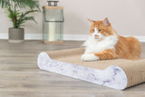 Eine braun-weiße Katze liegt entspannt auf einer Kratzmatte mit weiß-marmorierten Seiten auf einem Holzboden.