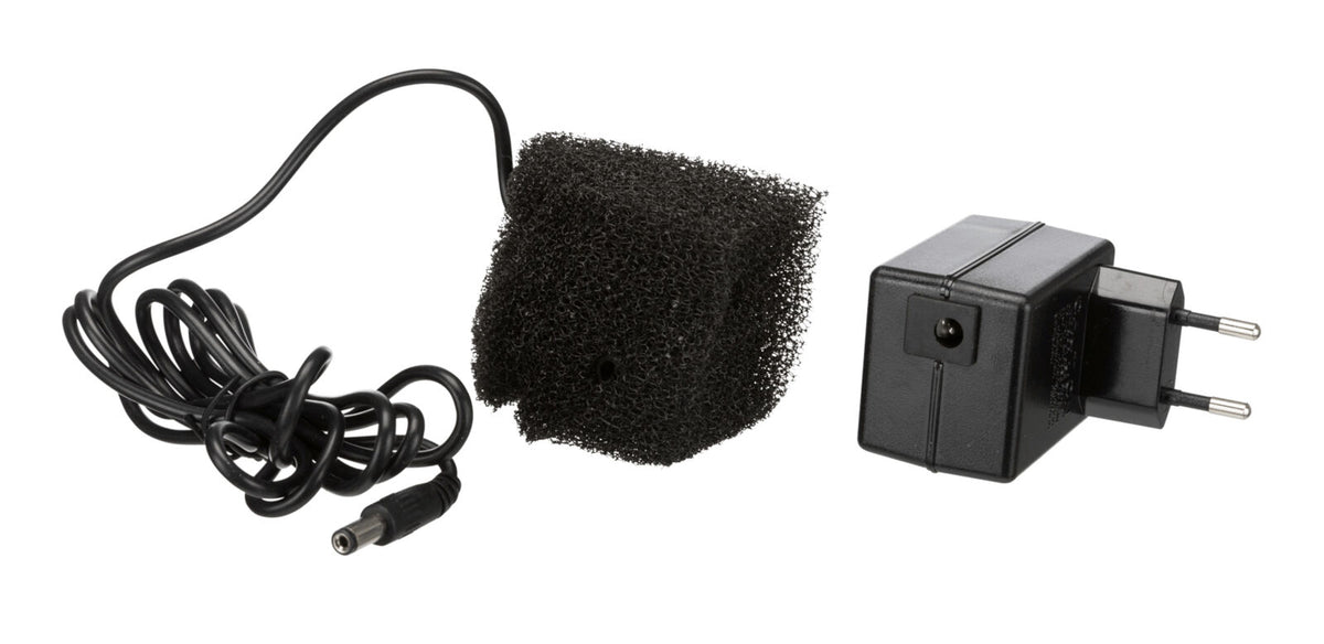 Schwarzes Netzteil mit EU-Stecker, schwarzem Kabel und einem quadratischen, schwarzen Schaumstoffstück.