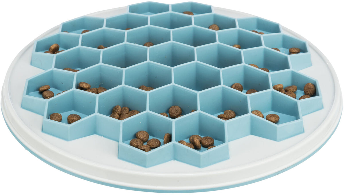 Runde blaue Futterschale mit hexagonalen Vertiefungen, teilweise mit braunen Kroketten gefüllt.