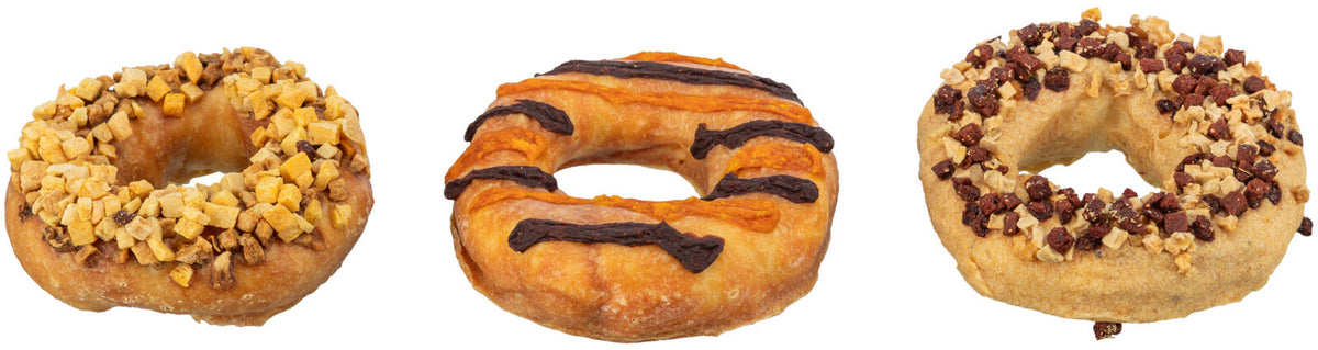 Drei Donuts mit verschiedenen Toppings: Links Apfelstücke, Mitte Schokolade und orange Glasur, Rechts rote und helle Stückchen.