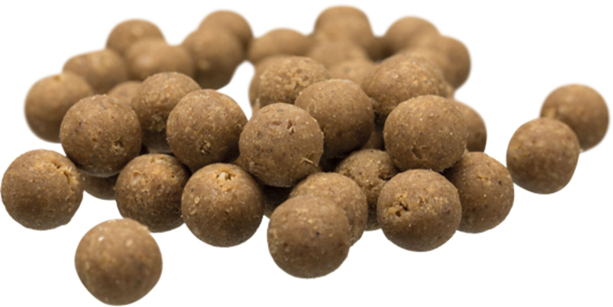 Braune, kugelförmige Futterpellets in verschiedenen Größen auf weißem Hintergrund verstreut.