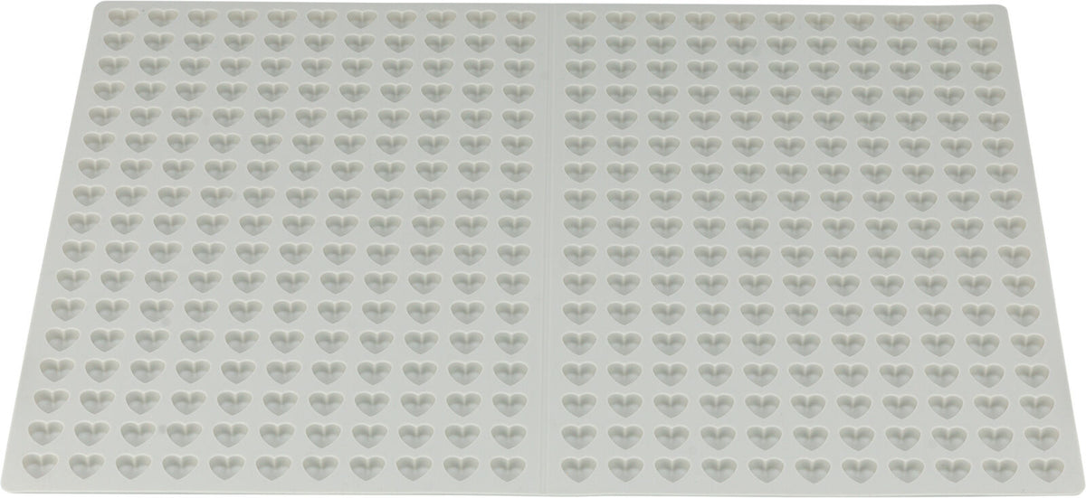Weiße Silikonform mit vielen herzförmigen Vertiefungen auf einer flachen Oberfläche.