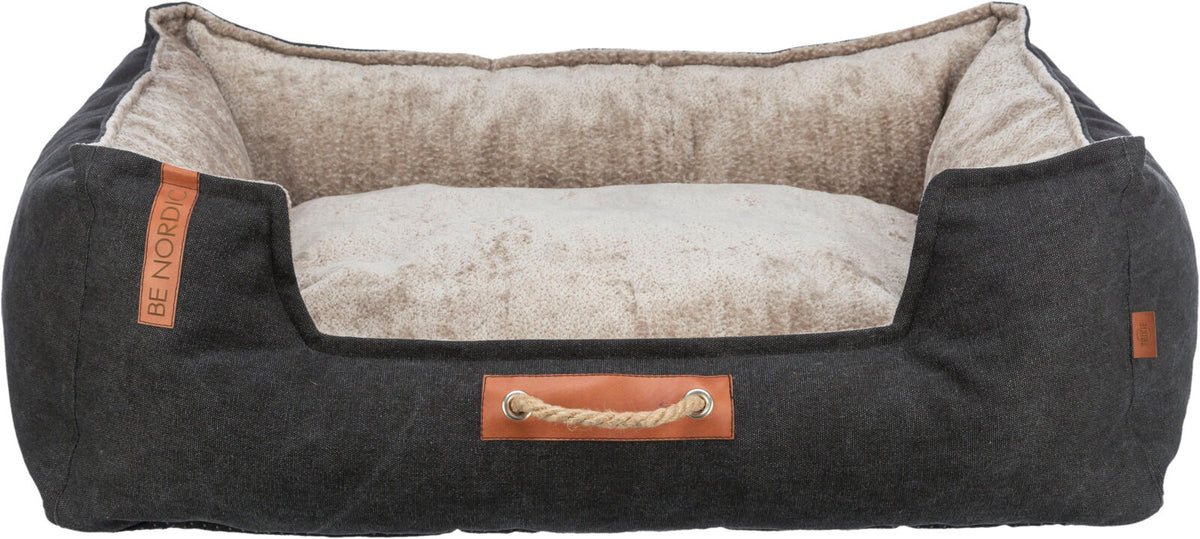 Hundebett mit dunkelgrauem Stoffbezug und heller, weicher Innenseite, vorne mit braunem Lederdetail und Seilgriff.