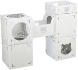 Weiße, modular aufgebaute Kartonboxen, teils verbunden, mit runden und katzenförmigen Ausschnitten, im Vordergrund.