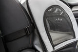 Grau-schwarzes Transportgerät im Auto, mit Netzfenster und Gurt an der Rückenlehne befestigt.