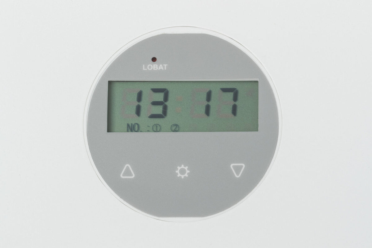 Rundes digitales Display mit grauem Hintergrund, zeigt die Uhrzeit 13:17 und an der Oberseite das Wort "LOBAT".