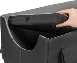Eine Hand hebt eine schwarze, gepolsterte Matte mit Reißverschluss aus einem gleichfarbigen, rechteckigen Behälter.