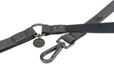 Graues Hundehalsband mit Metallring und Karabinerhaken, an dem ein rundes Trixie-Emblem hängt.