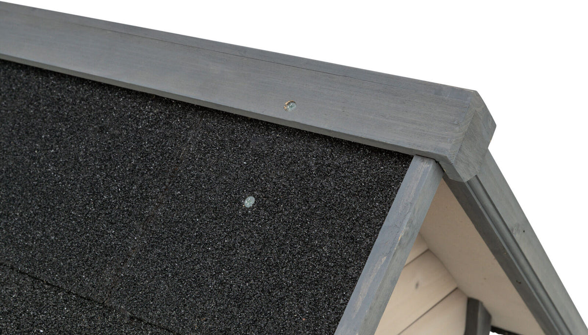 Schwarzes, grobkörniges Dachmaterial mit grau gestrichenem Holzrahmen, Detailaufnahme einer Konstruktionsektion.