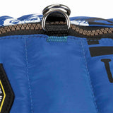 Blauer Stoff mit schwarzem und braunem Reißverschluss sowie silbernem D-Ring, teilweise sichtbares Logo.