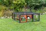 Kleintiergehege aus Metall mit Holzdetails auf grünem Rasen, innen zwei Kaninchen und Spielzeug.