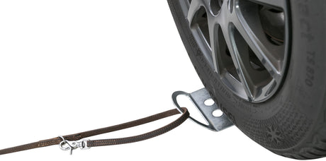 Nahaufnahme eines Autoreifens mit einem daran befestigten braunen Ledergurt über eine Metallhalterung.
