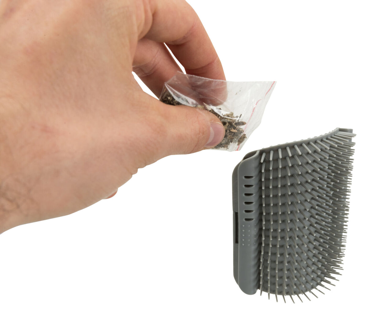 Eine Hand hält einen kleinen Beutel mit Kräutern neben einer grauen Bürste mit weichen Stacheln.